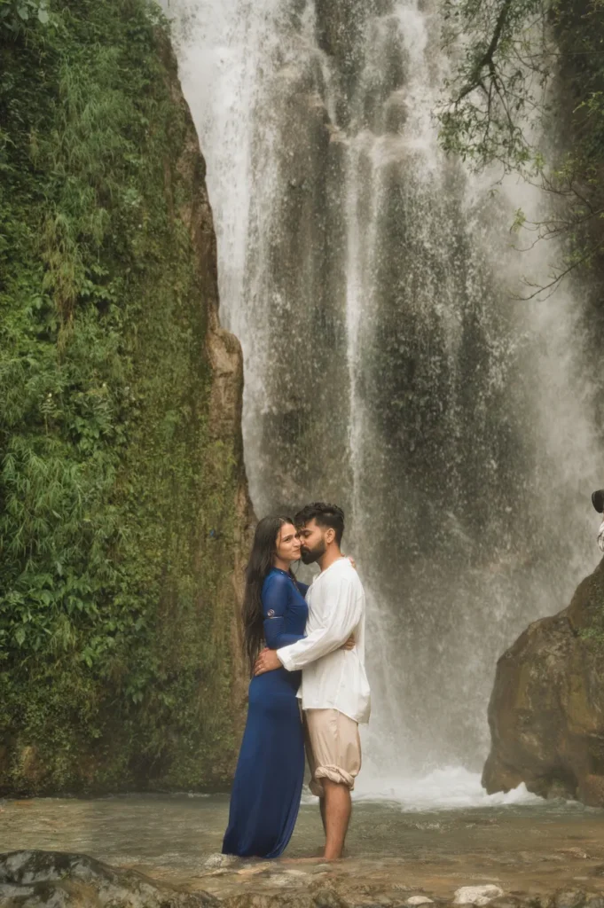 Romantic couple embracing in front of a majestic waterfall surrounded by lush greenery