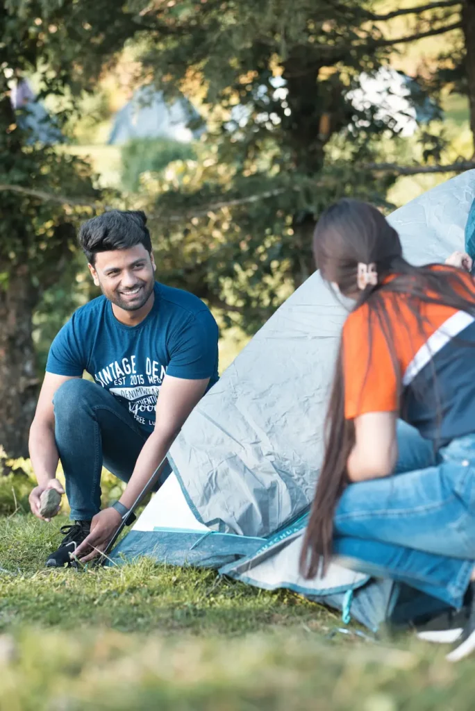 Couple setting up a campsite together in a forest clearing.