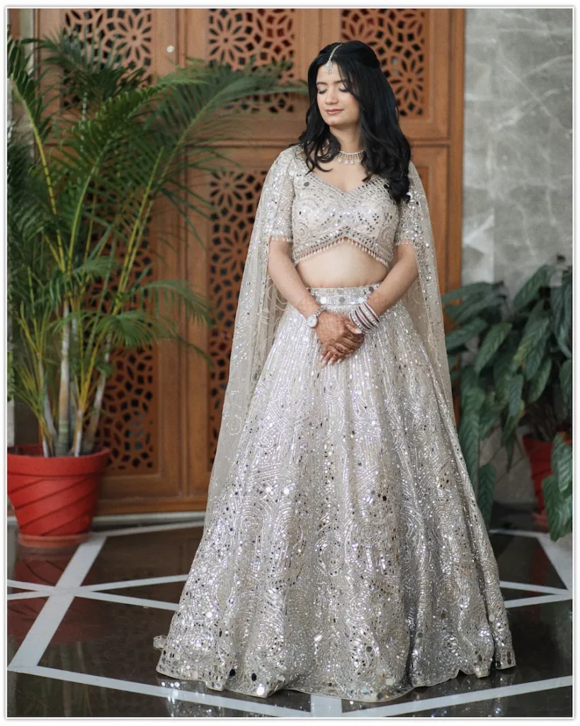 Graceful bridal portrait in a sparkling silver lehenga with soft natural light and elegant architectural backdrop.