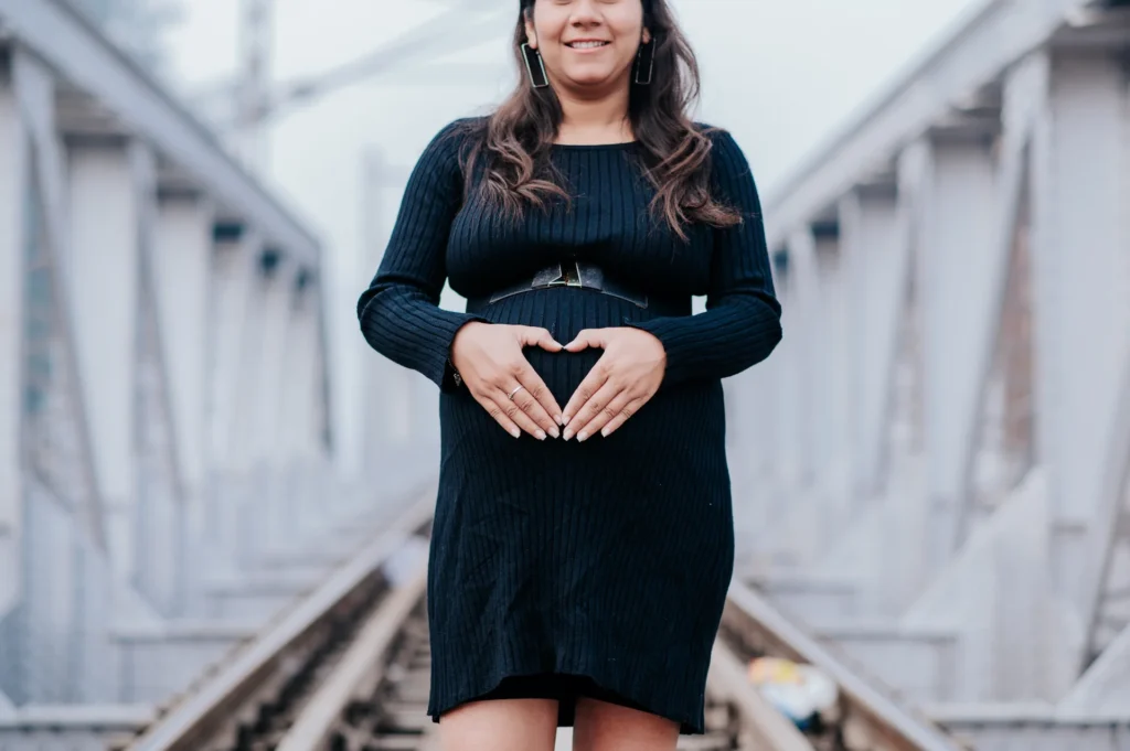 Elegant maternity shoot portrait of a mother-to-be posing on a railway bridge in Uttarakhand