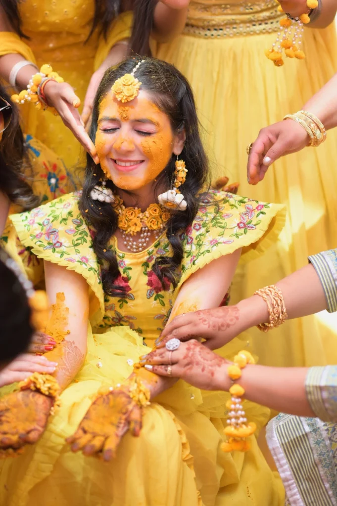 Bride smiling during a joyful haldi ceremony surrounded by family