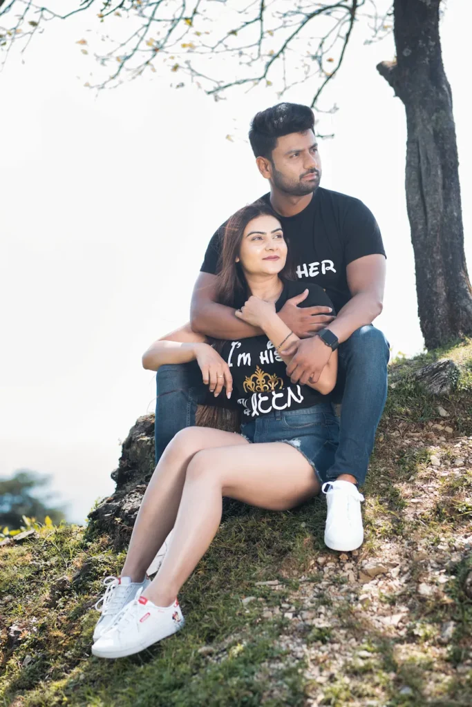 Relaxed outdoor portrait of a couple sitting beneath a tree overlooking the hills.
