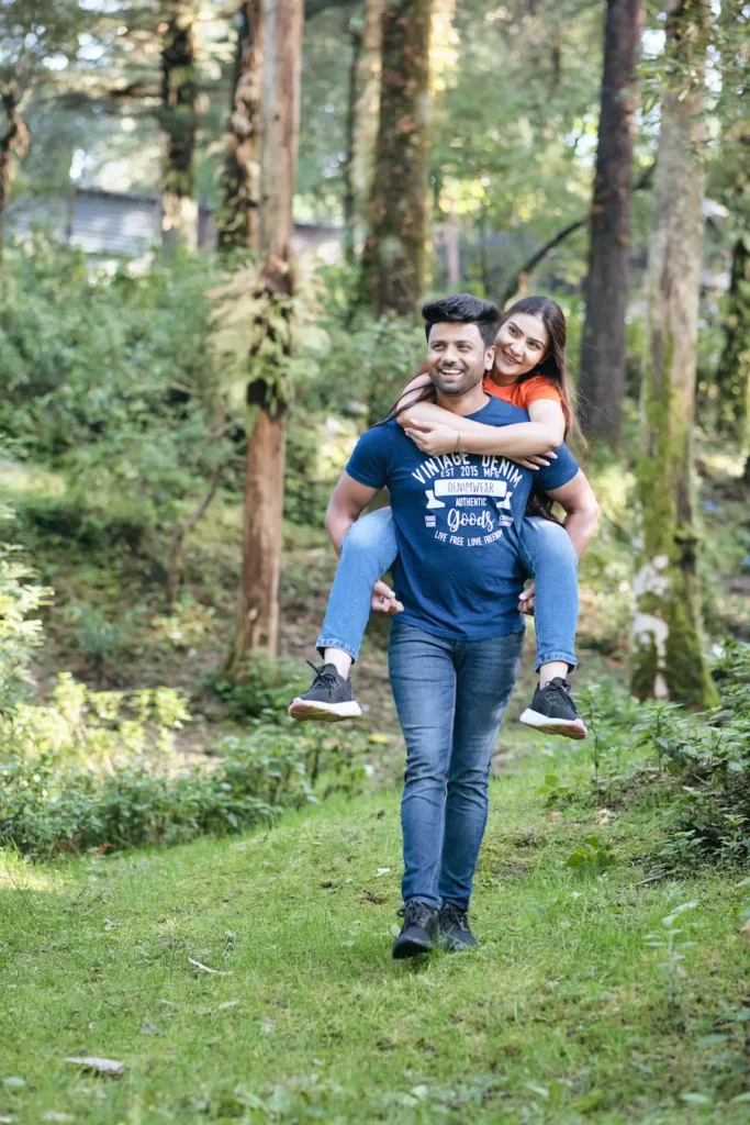 Playful outdoor portrait with one partner carrying the other through a forest trail.