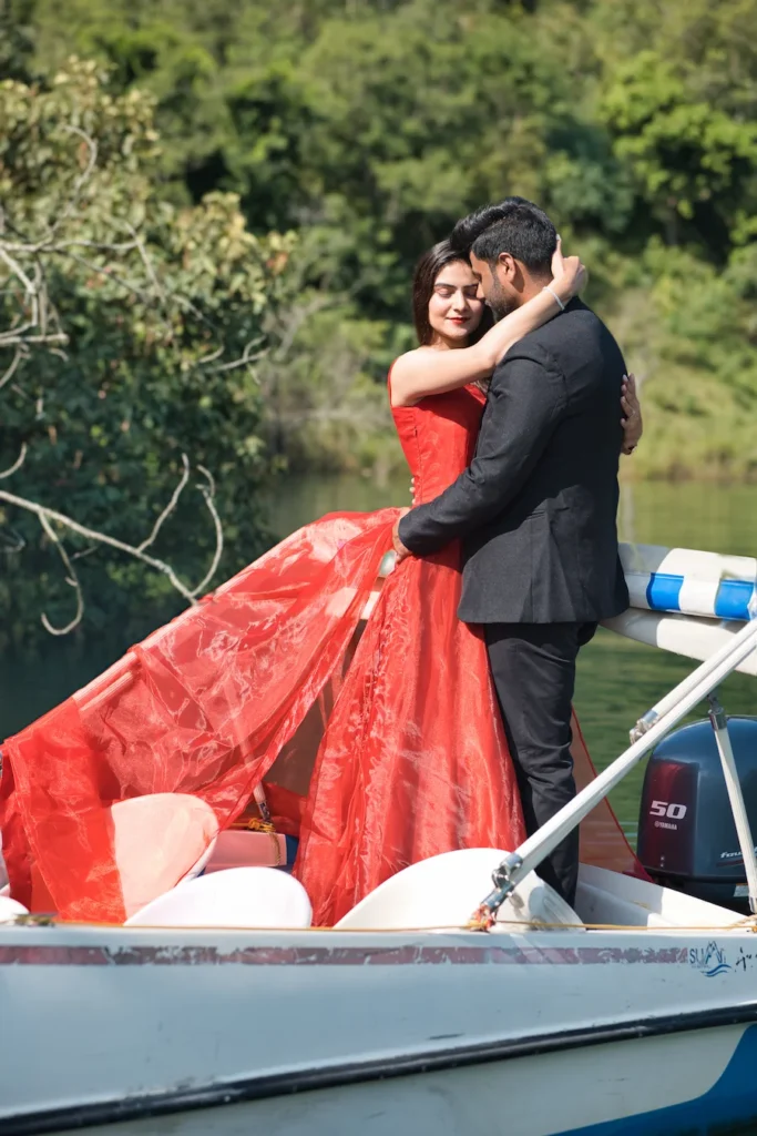 Romantic Tehri Pre Wedding Shoot at Tehri Lake featuring a couple embracing on a boat with scenic Uttarakhand landscapes in the background.