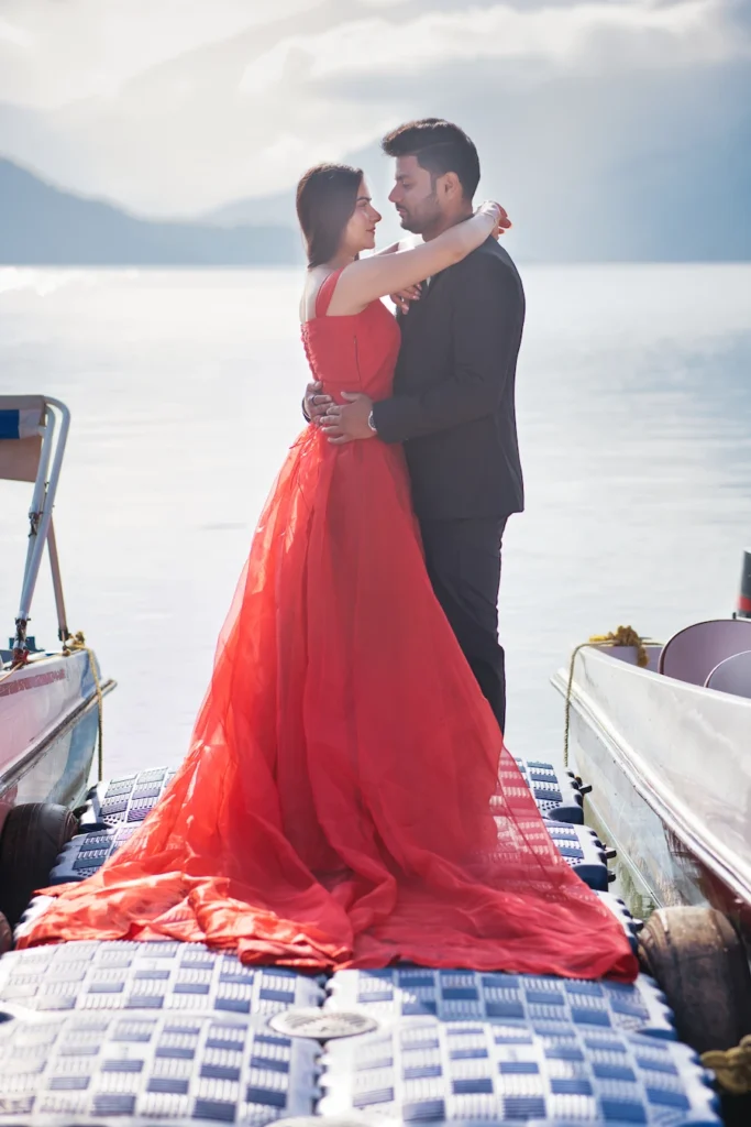 Elegant couple standing together on a lakeside jetty at sunset.