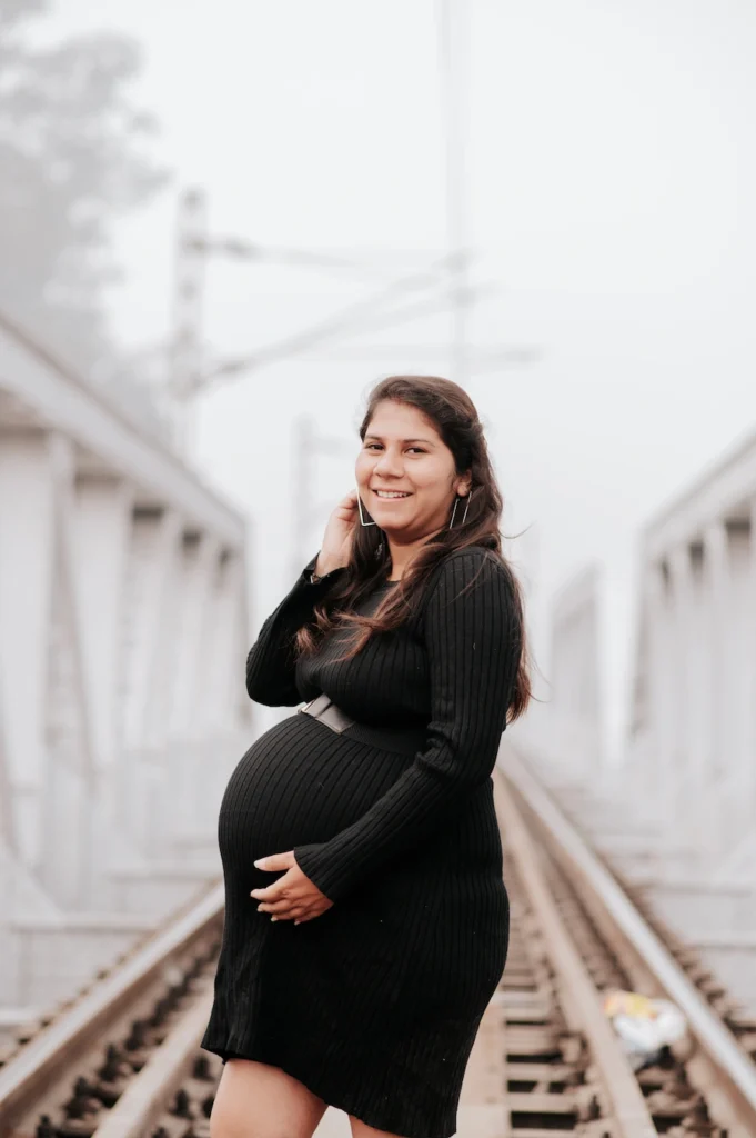 Mother-to-be posing gracefully on a railway bridge while celebrating the journey of motherhood