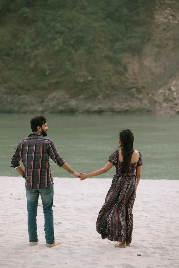 Couple walking hand in hand along a serene riverside surrounded by nature