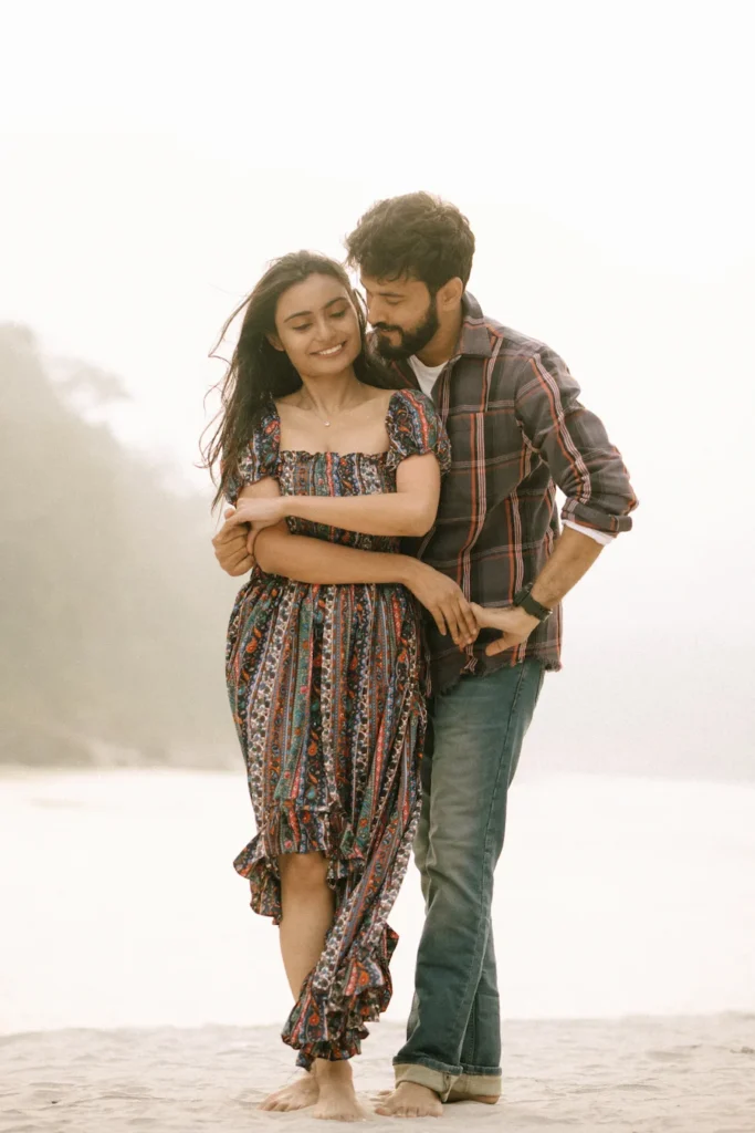 Romantic couple embracing with soft expressions beside a tranquil river during golden hour