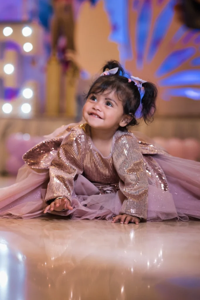 Smiling toddler in a sparkly party dress during an indoor birthday celebration