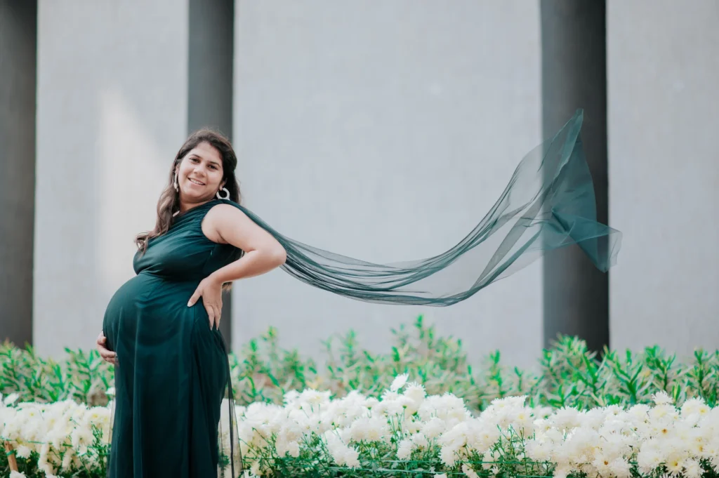 Mother-to-be posing confidently in an elegant gown with flowing fabric during an outdoor portrait session