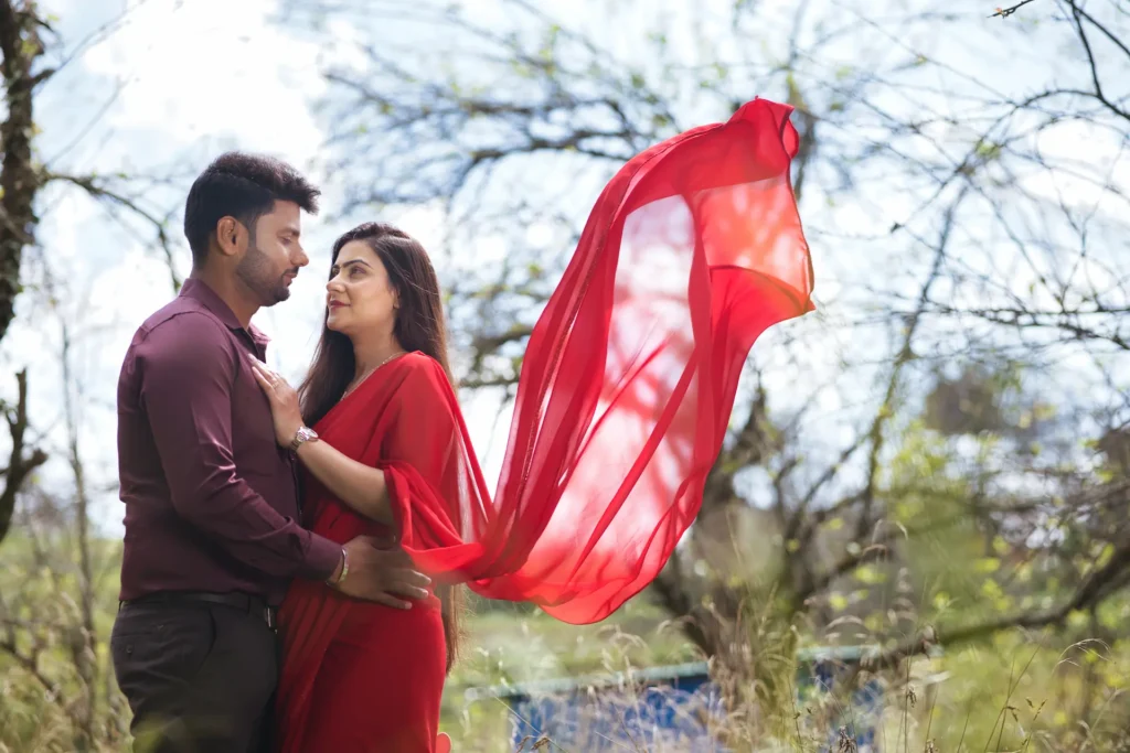 Couple sharing a romantic moment as a flowing red scarf moves gracefully in the breeze.