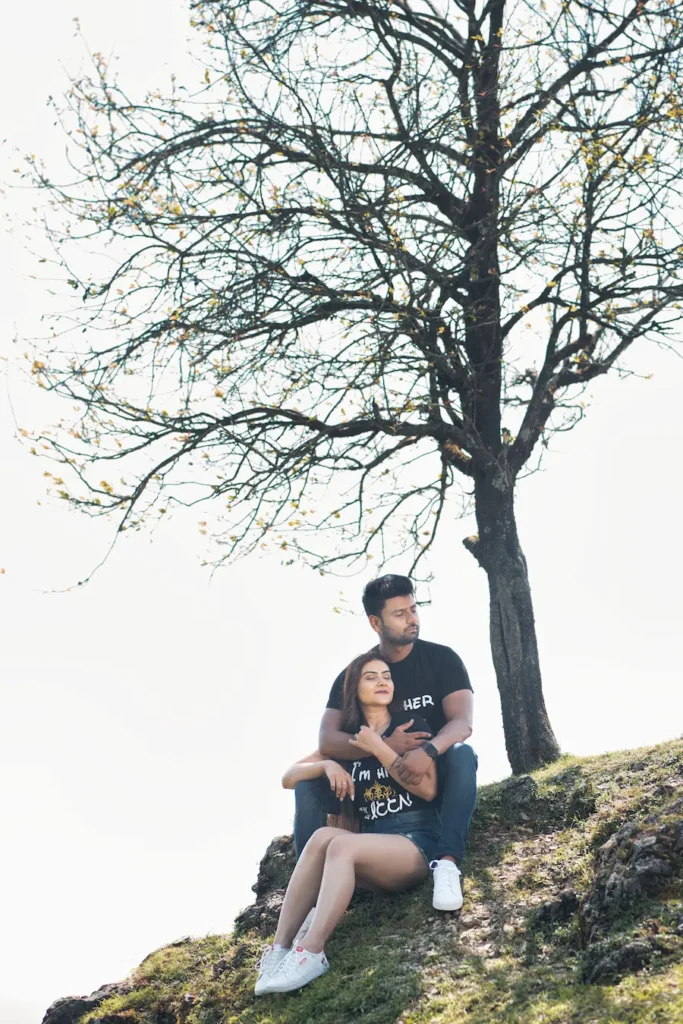 Couple relaxing beneath a tree with mountain views in the background.
