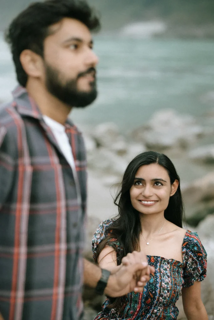 Couple holding hands with the bride looking back and smiling during a scenic riverside session