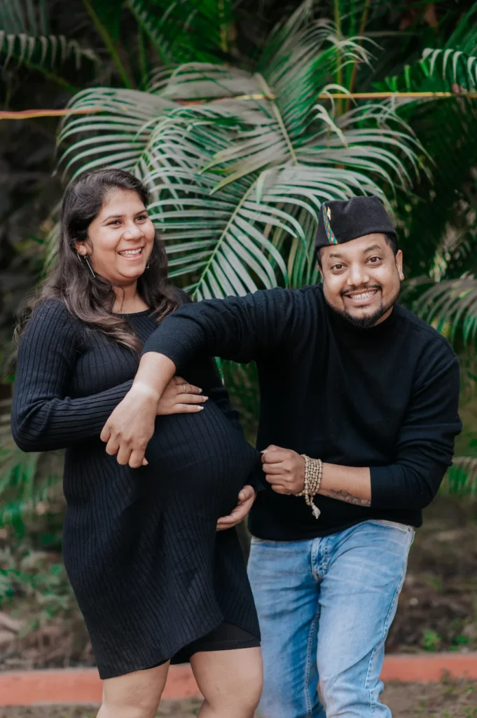 Expecting couple sharing a joyful moment surrounded by lush greenery during an outdoor pregnancy photoshoot