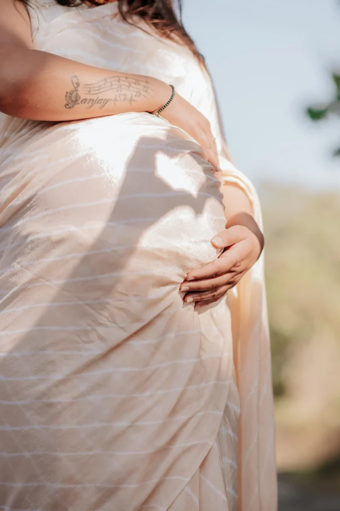 Close-up portrait highlighting a baby bump with soft natural light and artistic shadows