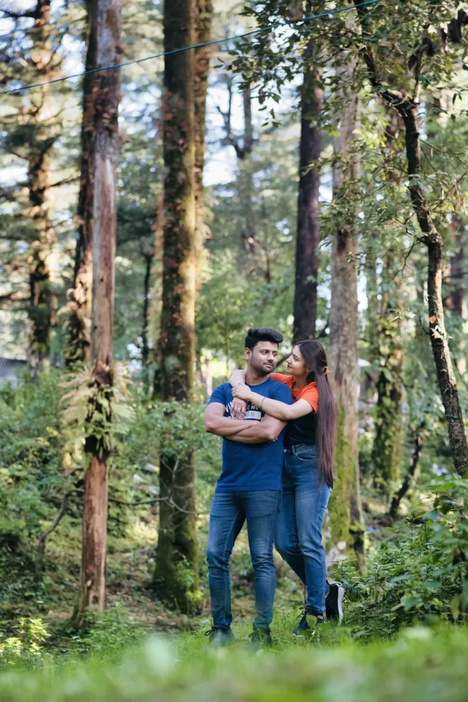 Couple embracing in a peaceful forest surrounded by tall pine trees.