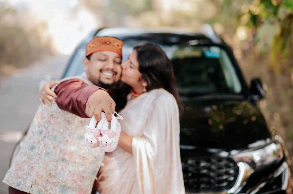 Expecting couple holding baby shoes and sharing a loving embrace during an outdoor portrait session