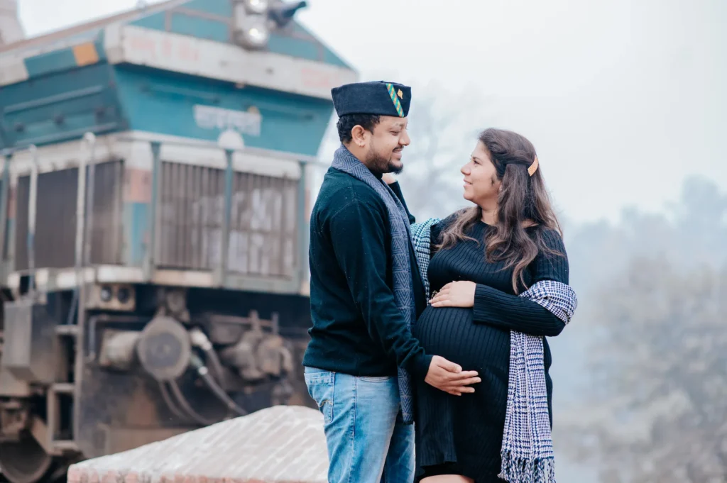 Couple standing together near a train track while celebrating their journey into parenthood