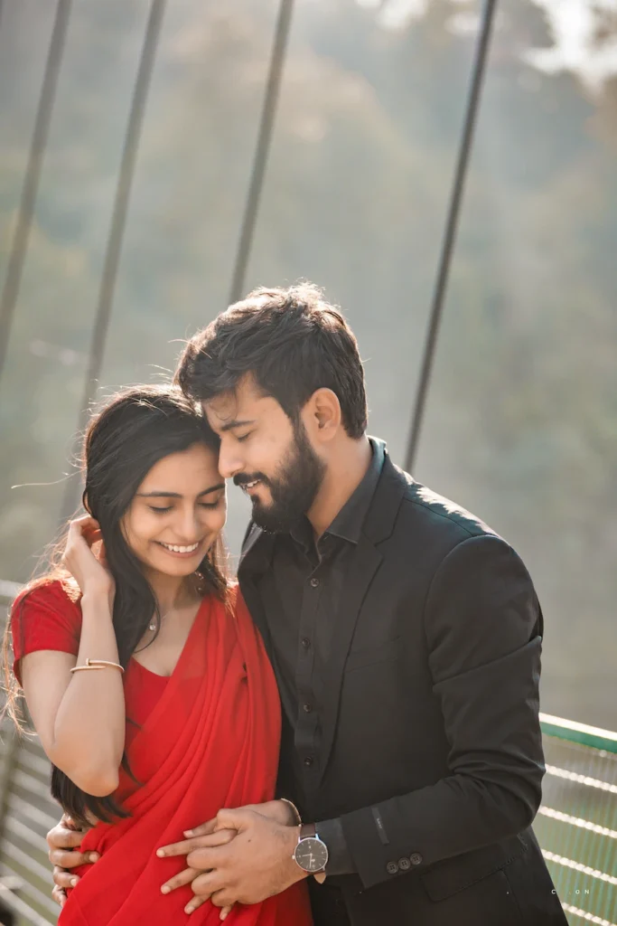 Smiling couple enjoying a candid pre-wedding portrait on a suspension bridge at golden hour