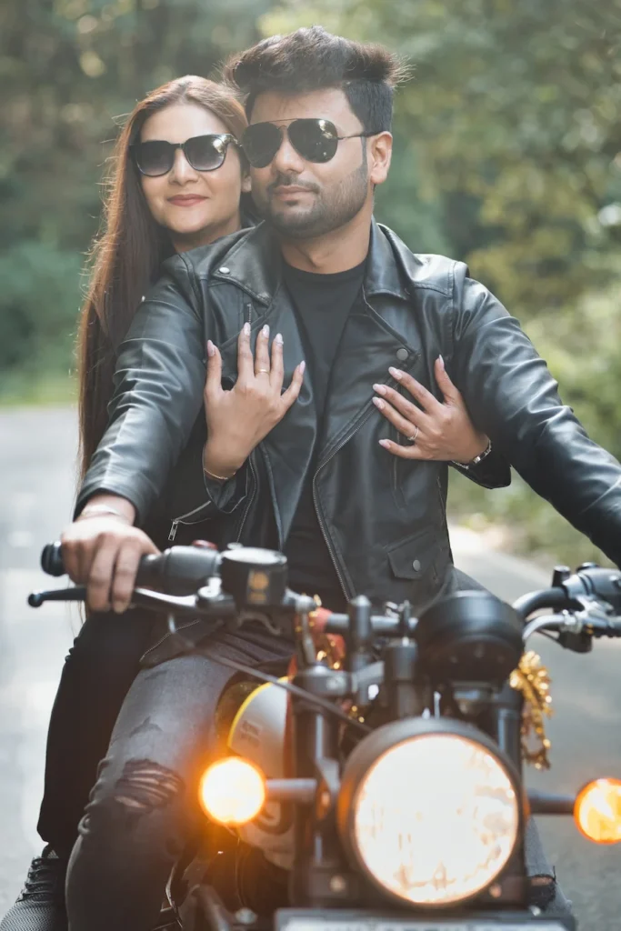 Stylish couple posing on a motorcycle wearing matching sunglasses.