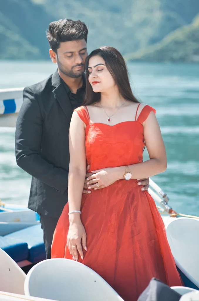 Couple posing on a boat with a flowing red dress creating a dramatic effect.