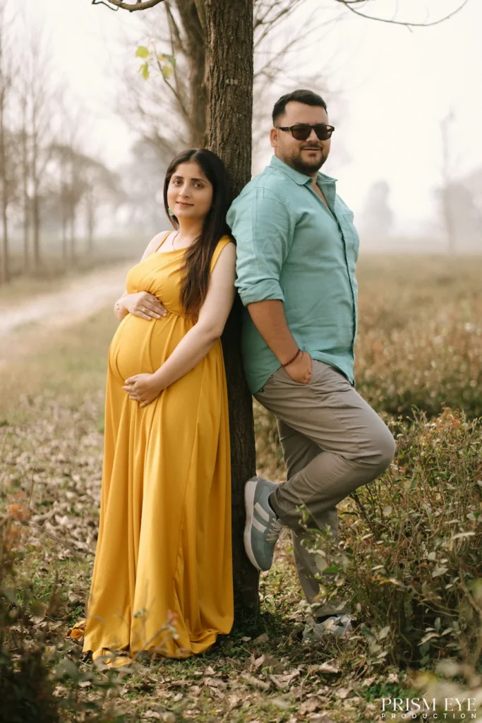 Mother-to-be and her partner posing together beside a tree during a peaceful outdoor maternity session.