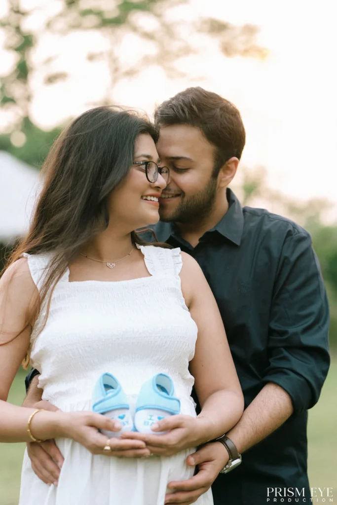 Pregnant couple holding baby shoes during a heartfelt maternity photography session.