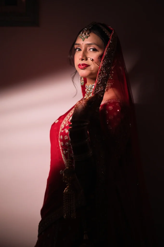 Bridal portrait with dramatic lighting showcasing traditional attire and elegant jewelry.