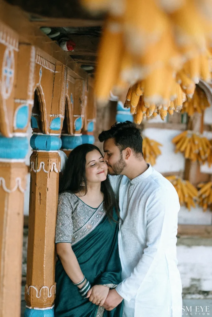 Couple enjoying an intimate moment beneath carved wooden pillars and hanging corn decorations