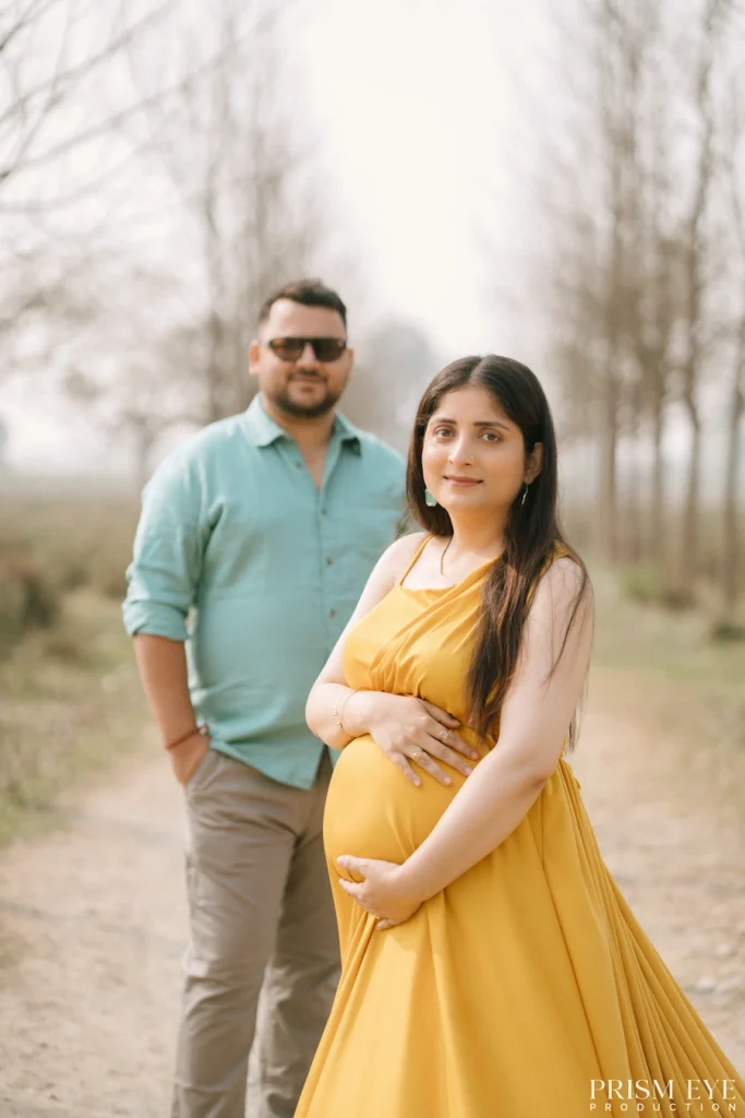 Pregnant woman posing confidently while her partner stands proudly in the background.