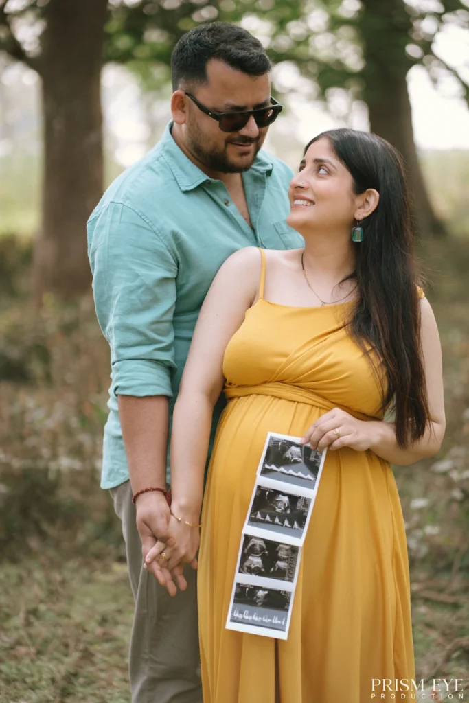 Expecting mother holding ultrasound images while smiling beside her supportive partner.