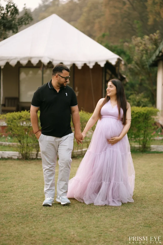 Expecting couple walking hand in hand through a peaceful garden during an outdoor maternity session.