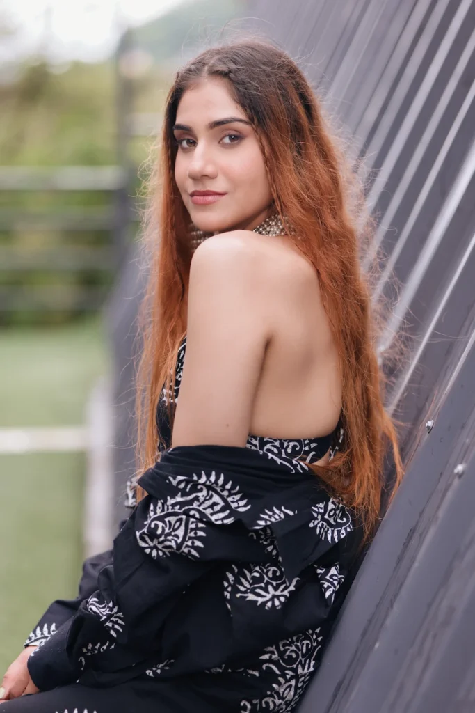 Woman posing in a stylish black printed co-ord set against a modern architectural backdrop.