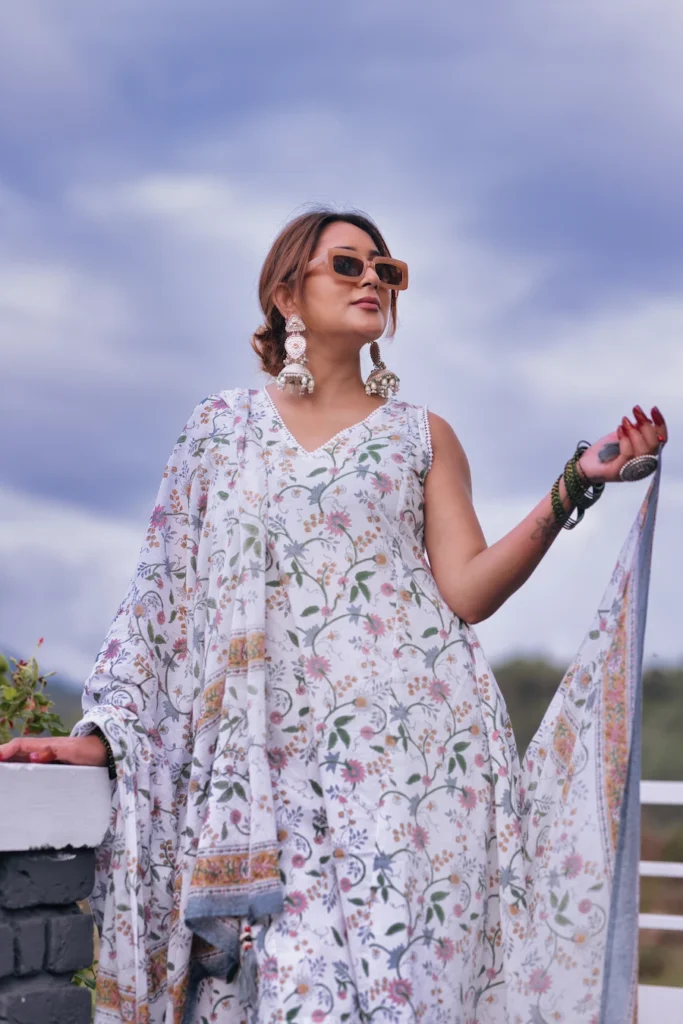 Fashion portrait of a woman wearing a floral ethnic outfit under dramatic cloudy skies.