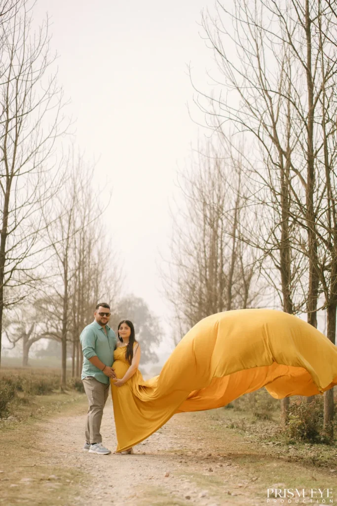 Outdoor maternity portrait featuring a flowing yellow dress creating a graceful and artistic composition.