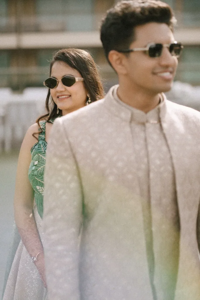 Stylish groom portrait with the bride smiling in the background during the engagement.