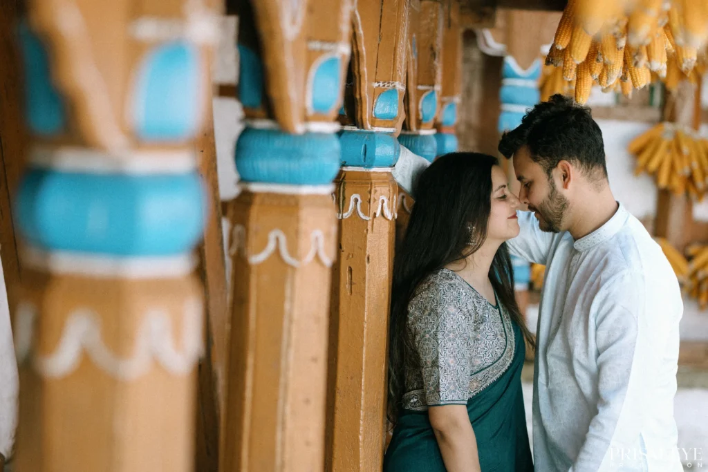 Romantic couple sharing an intimate moment beside carved wooden pillars in a traditional village setting