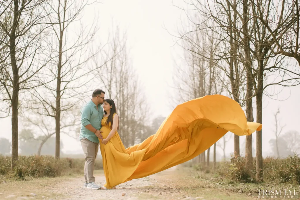 Couple posing with a flowing maternity dress during a maternity shoot in Dehradun surrounded by beautiful outdoor scenery.