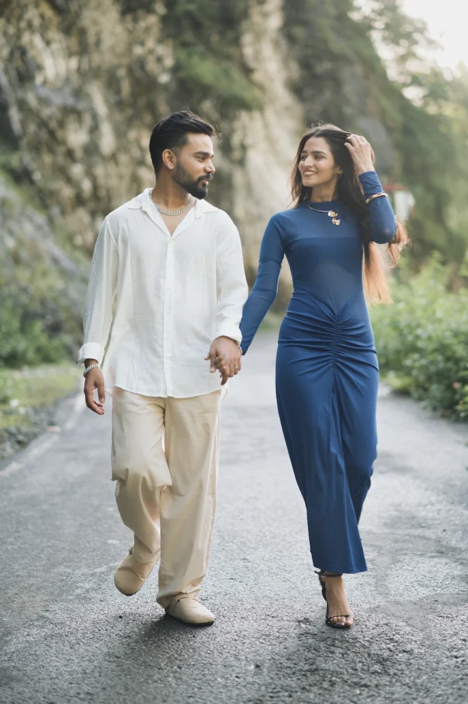 Couple holding hands and walking together during a romantic pre-wedding photoshoot in nature.