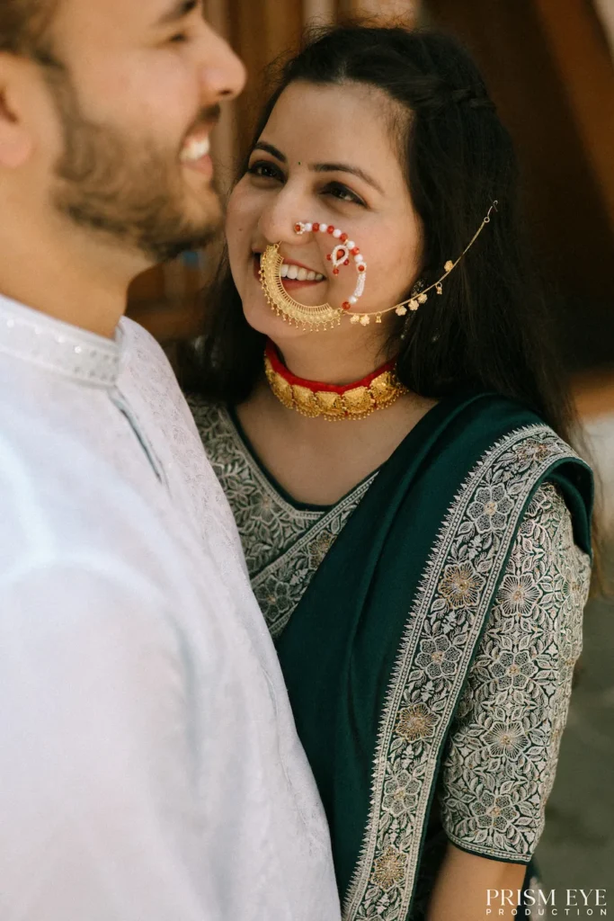 Smiling couple sharing a romantic embrace in front of a traditional corn-decorated village house