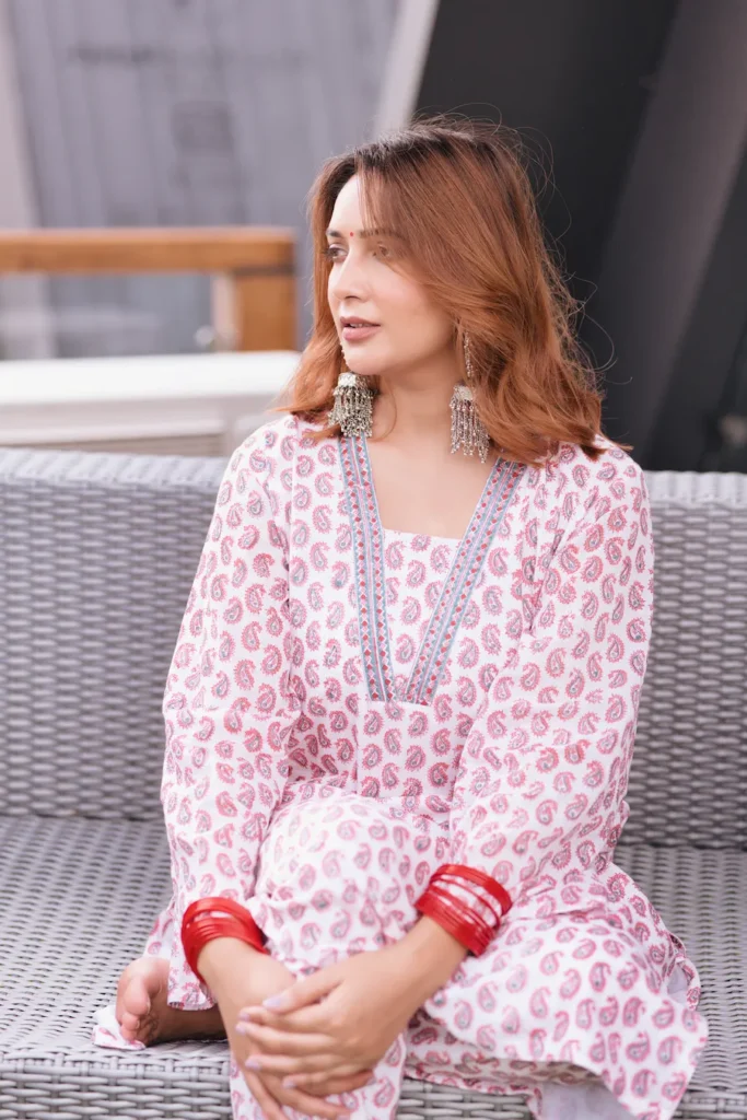 Elegant portrait of a woman in a printed kurta sitting outdoors with traditional accessories.