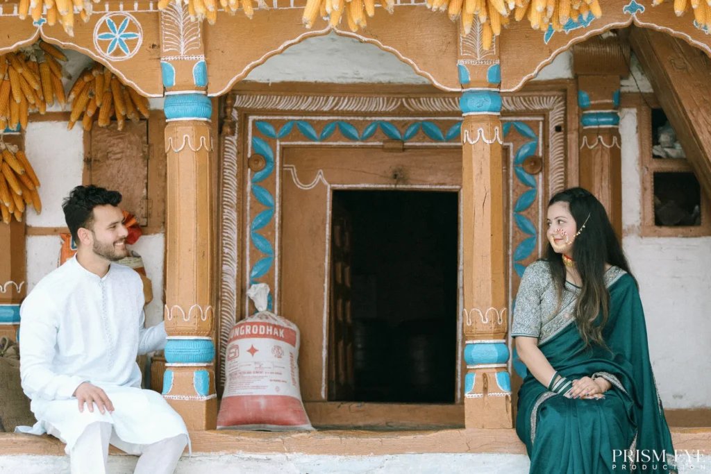 Couple enjoying a candid conversation while seated outside a traditional wooden village house