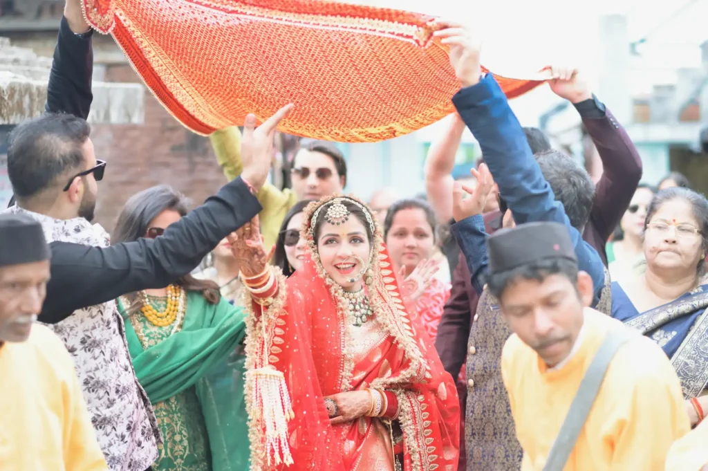 Bride making her ceremonial entrance beneath a traditional bridal canopy during an Indian wedding.