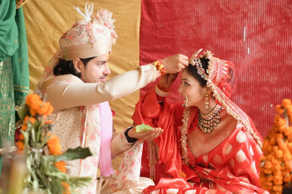 Groom applying sindoor to the bride during a traditional Hindu wedding ritual.