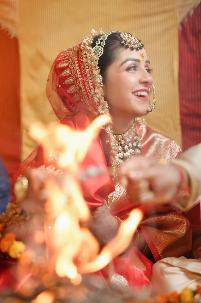 Bride smiling during a sacred fire ritual at a Triyuginarayan Wedding, showcasing timeless traditions and elegant bridal attire.