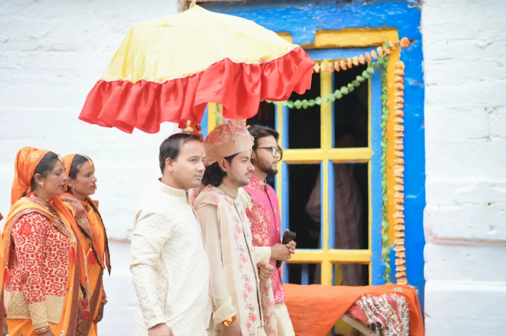 Wedding procession arriving at the temple with family members and traditional ceremonial umbrella.