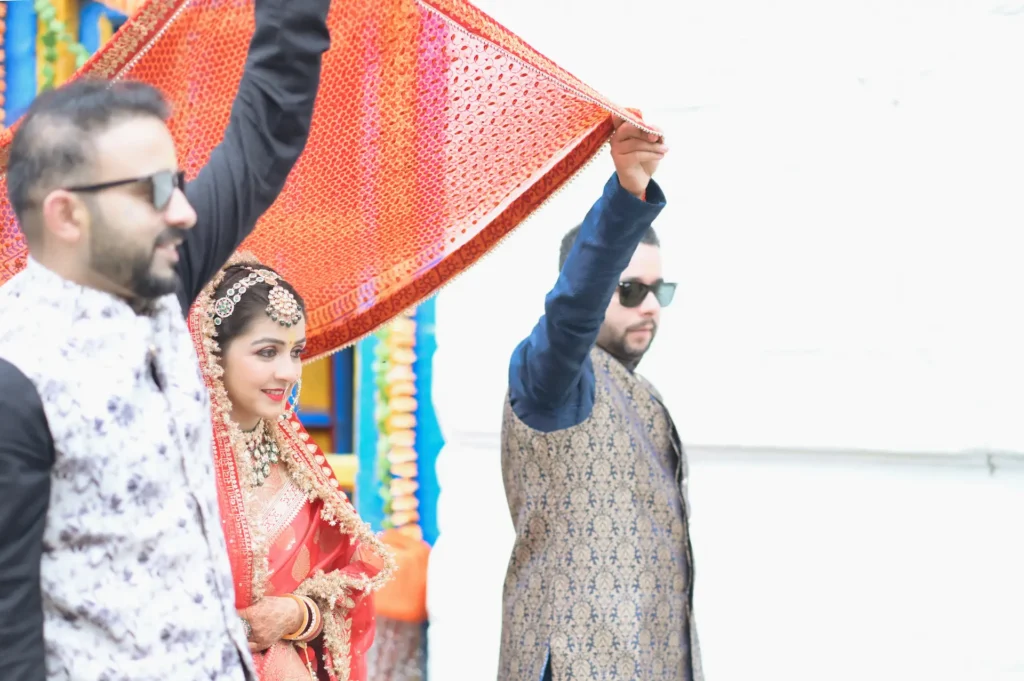 Bride entering the wedding ceremony under a decorative canopy surrounded by family.