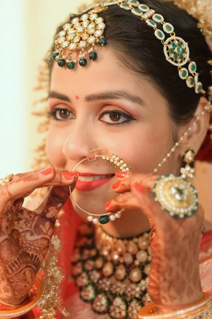Close-up bridal portrait showcasing intricate nose ring, bridal jewelry, and detailed mehndi.