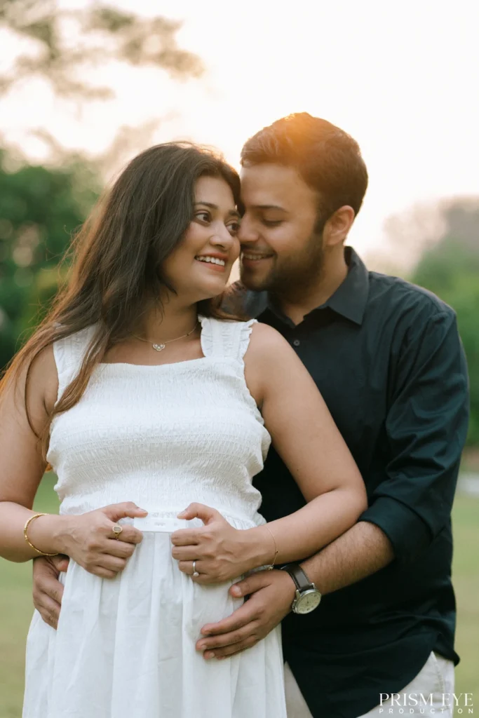 Romantic portrait of an expecting couple embracing and smiling during an outdoor pregnancy session.