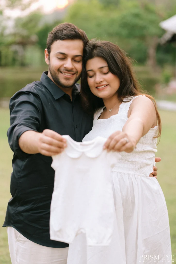 Parents-to-be holding a newborn onesie while celebrating the joy of their growing family.